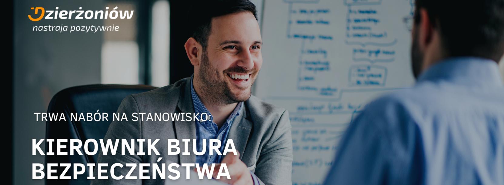 dwóch mężczyzn w błekitnych koszulach rozmawia przy biurku, logo miasta w roku, napis nabór na stanowisko kierownika biura bezpieczeństwa