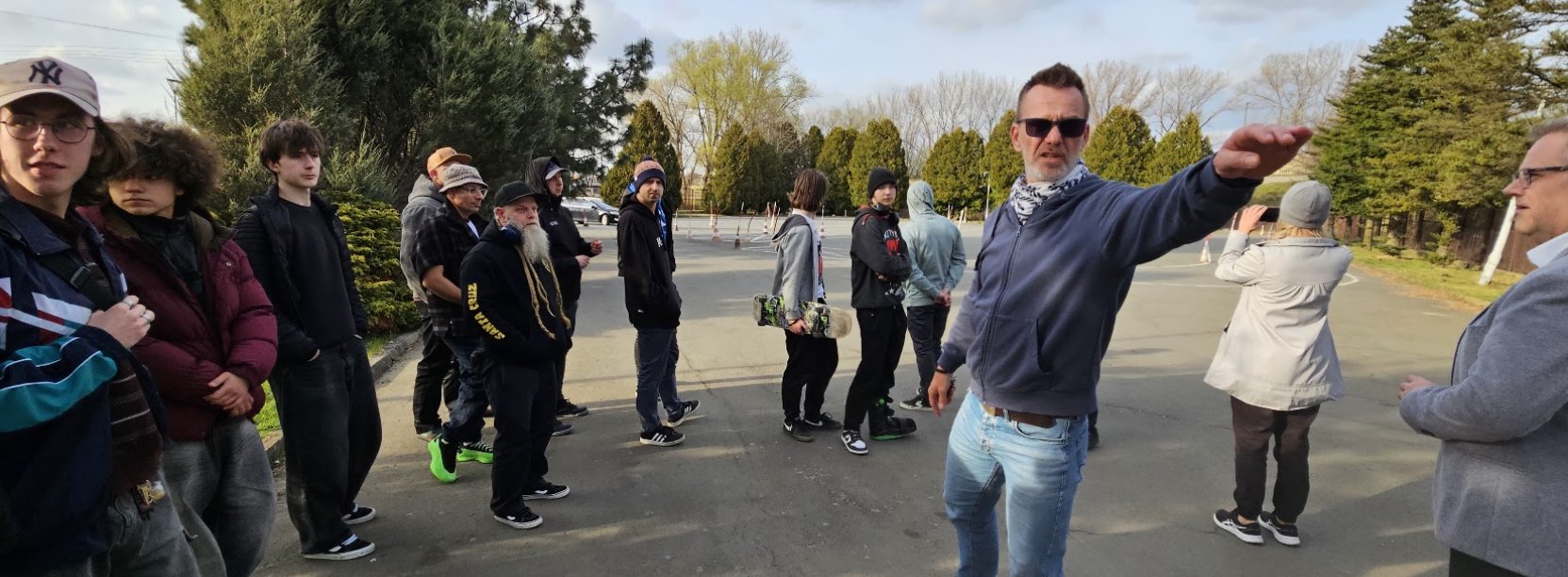 Grupa mężczyzn na placu manewrowym, jeden z nich coś pokazuje ręką