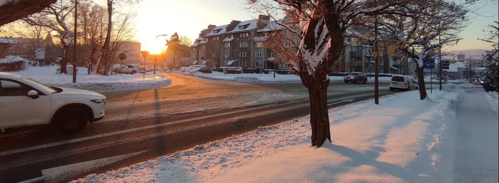 zimowa aura na ul. batalionów chłopskich, przejeżdzający biały samochód, ośnie zone chodniki i drzewa