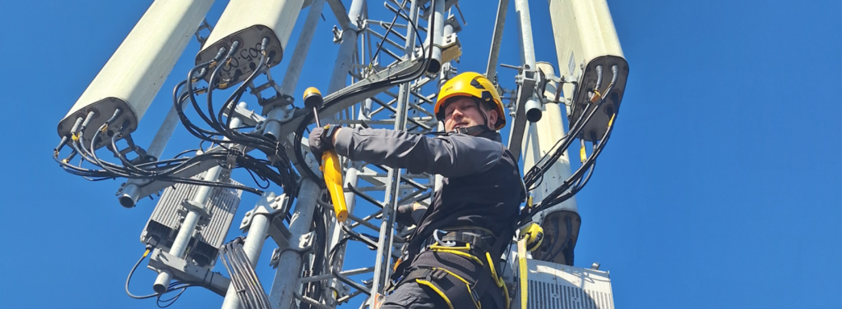 pracownik robót wysokościowych na nadajniku telefonii komórkowej
