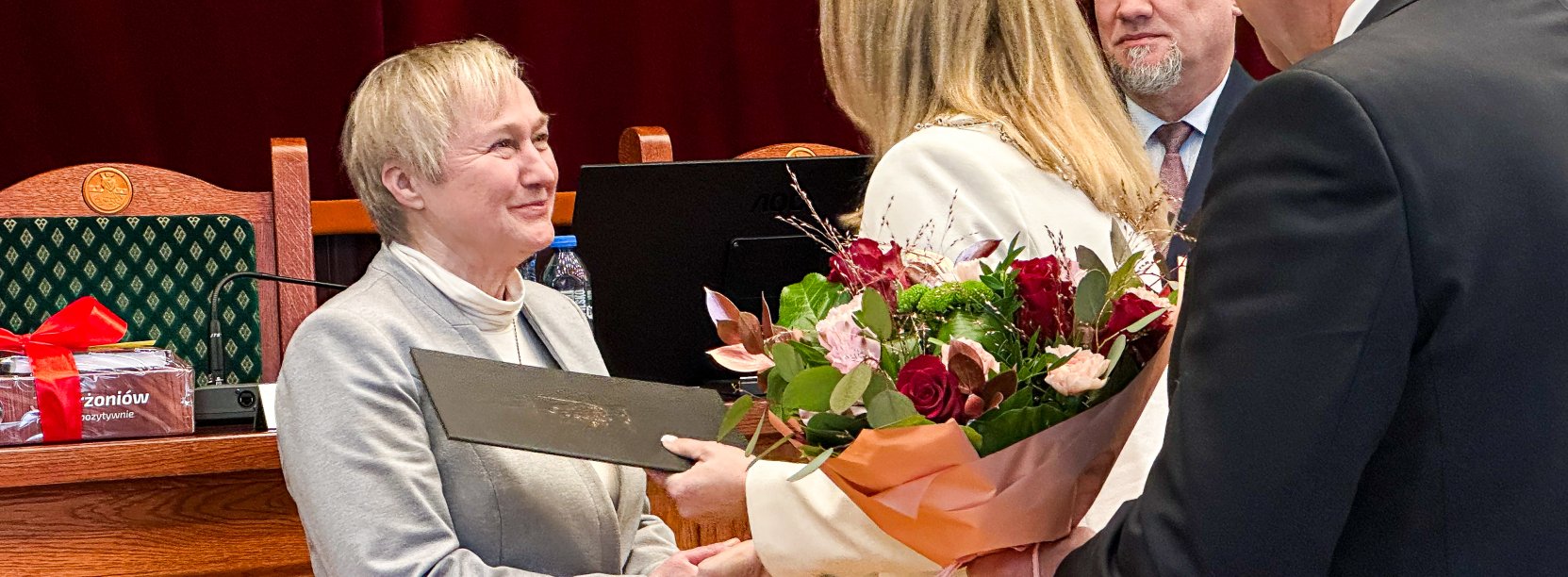 Lucyna Musiał przyjmuje gratulacje i kwiaty z okazji odejścia na emeryturę