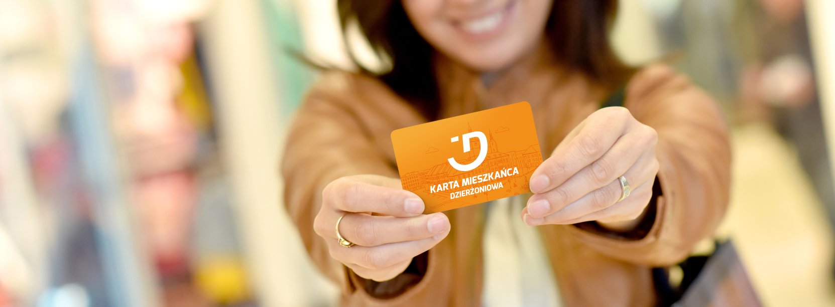 Uśmiechnięta kobieta trzyma w rękach kartę mieszkańca Dzierżoniowa
