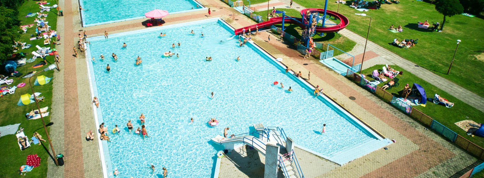 zdjęcie z lotu ptaka, dwie niecki basenowe na terenie OSiR-u, w wodzie kąpiący się ludzie