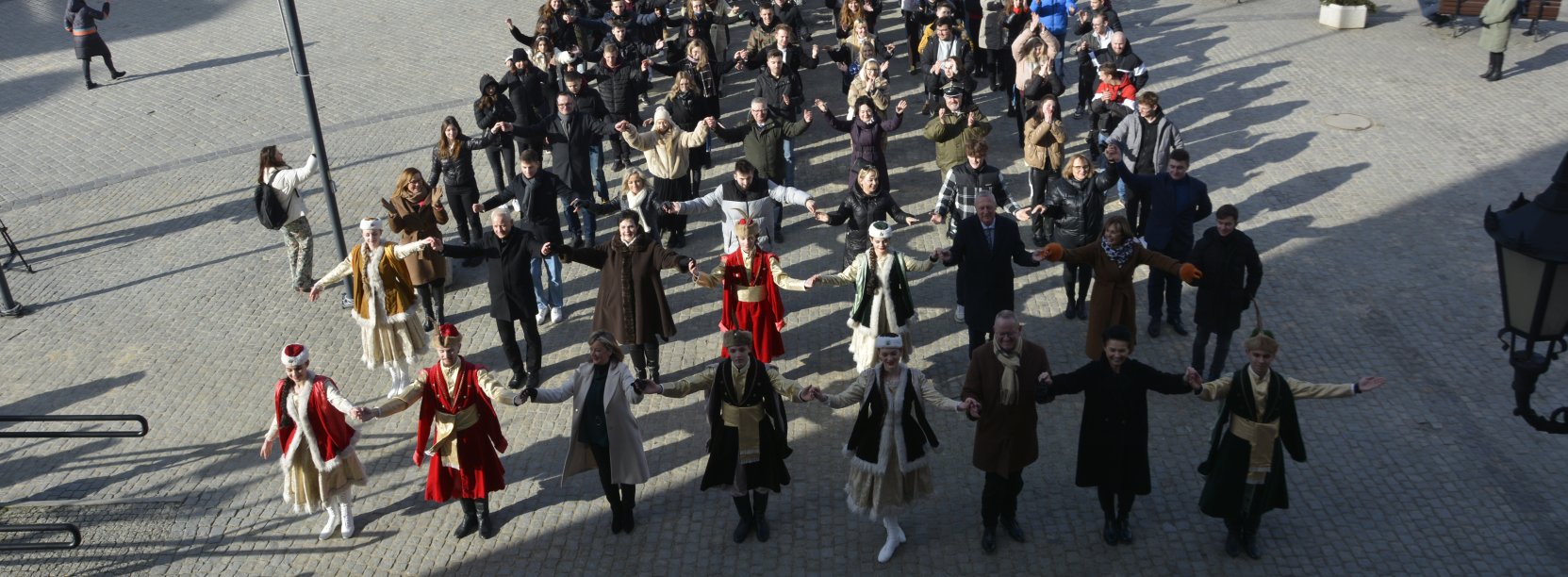 Duża grupa tanczących poloneza osób na płycie rynku