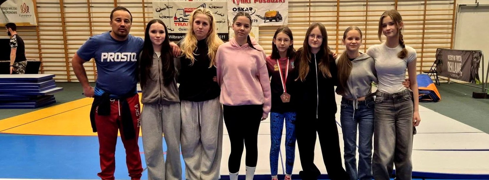 grupa zawodniczek z trenerem na hali sportowej