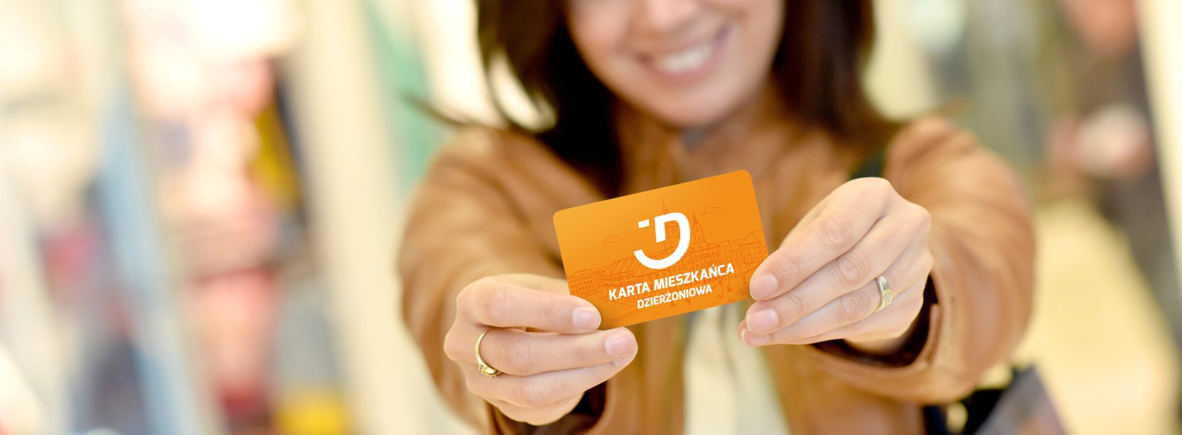 uśmiechnnięta kobieta trzyma w rękach kartę meiszkańca Dzierzoniowa
