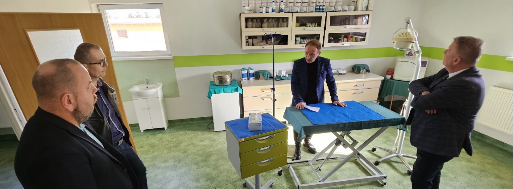 czterecvh mężczyzn w ambulatorium dla zwierząt, stoją wokół stołu zabiegowego, oglądają pomieszczenie 
