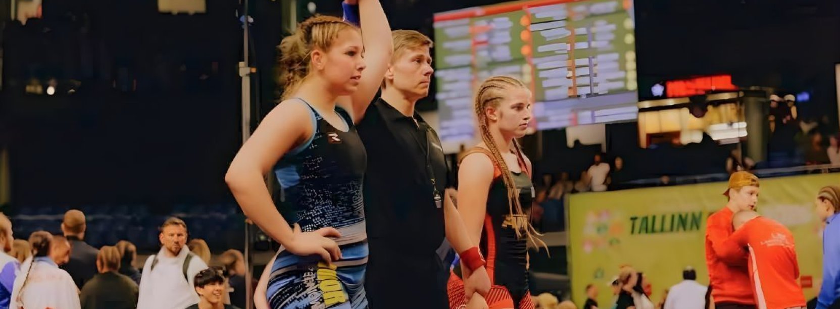 Dwie zapaśniczki, po środku sędzia unoszący rękę zwyciężczyni walki