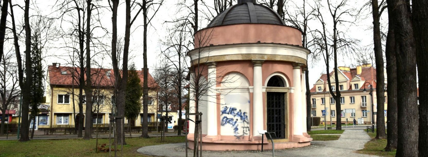 Niewielka, okrągła kaplica w parku, z rzeźbą kobiety wieńczącej kopułę