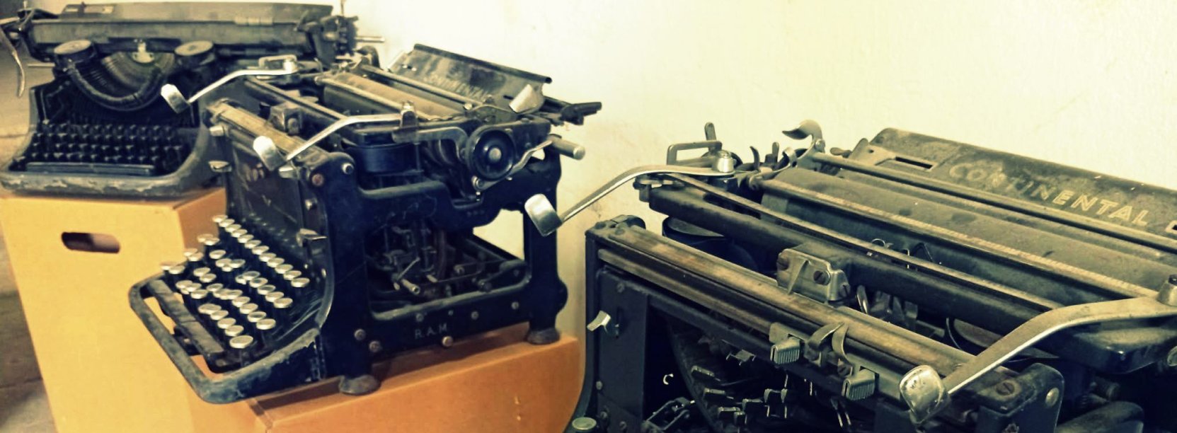 Trzy stare maszyny do pisania na kartonowych pudełkach