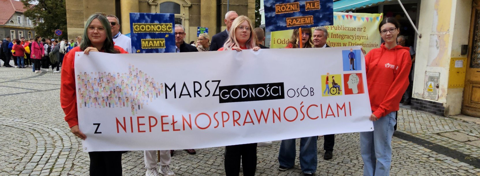 Trzy dziewczyny trzymające baner z napisem "Marsz osób z niepełnosprawnościami"
