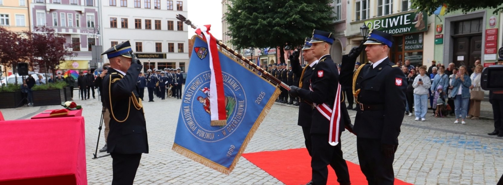 Oficer straży pożarnej salutuje przed sztandarem