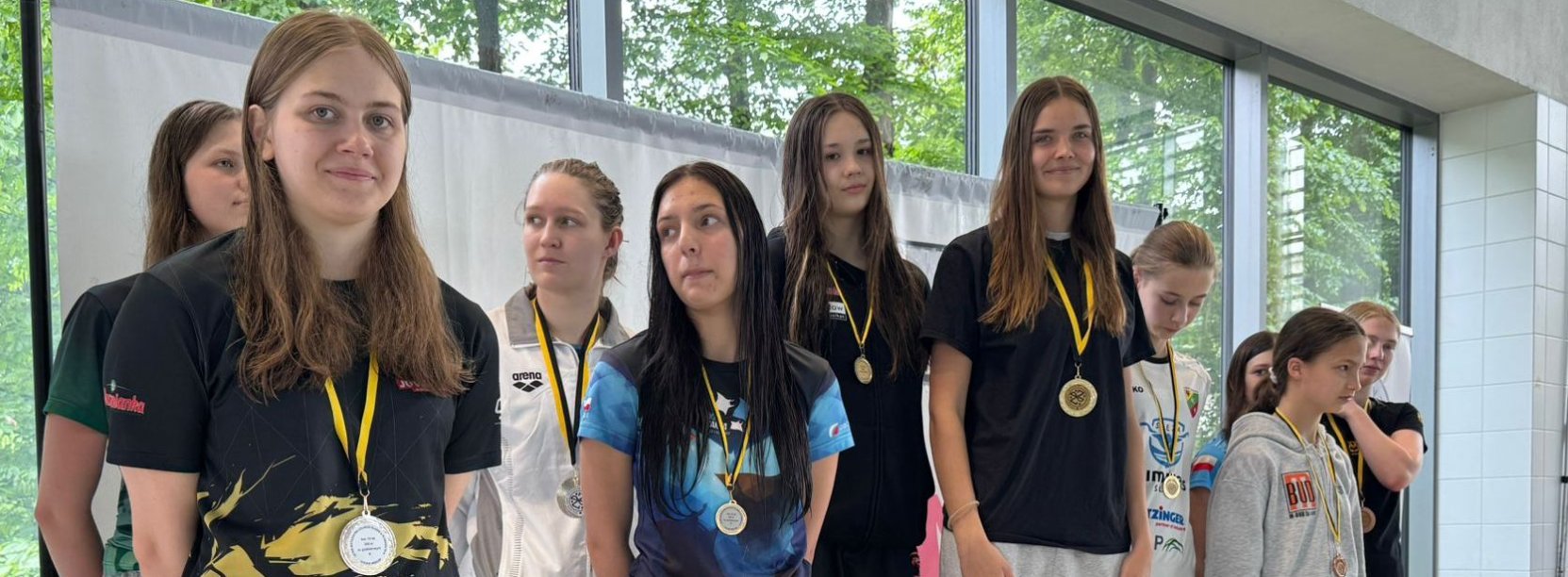 Grupa pływaczek na wspólnym zdjęciu, każa ma na szyi medal