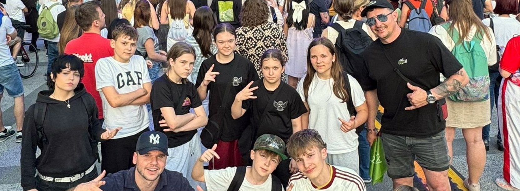 Kilkunastu młodych tancerzy na wspólnym zdjęciu, za nimi duża scena