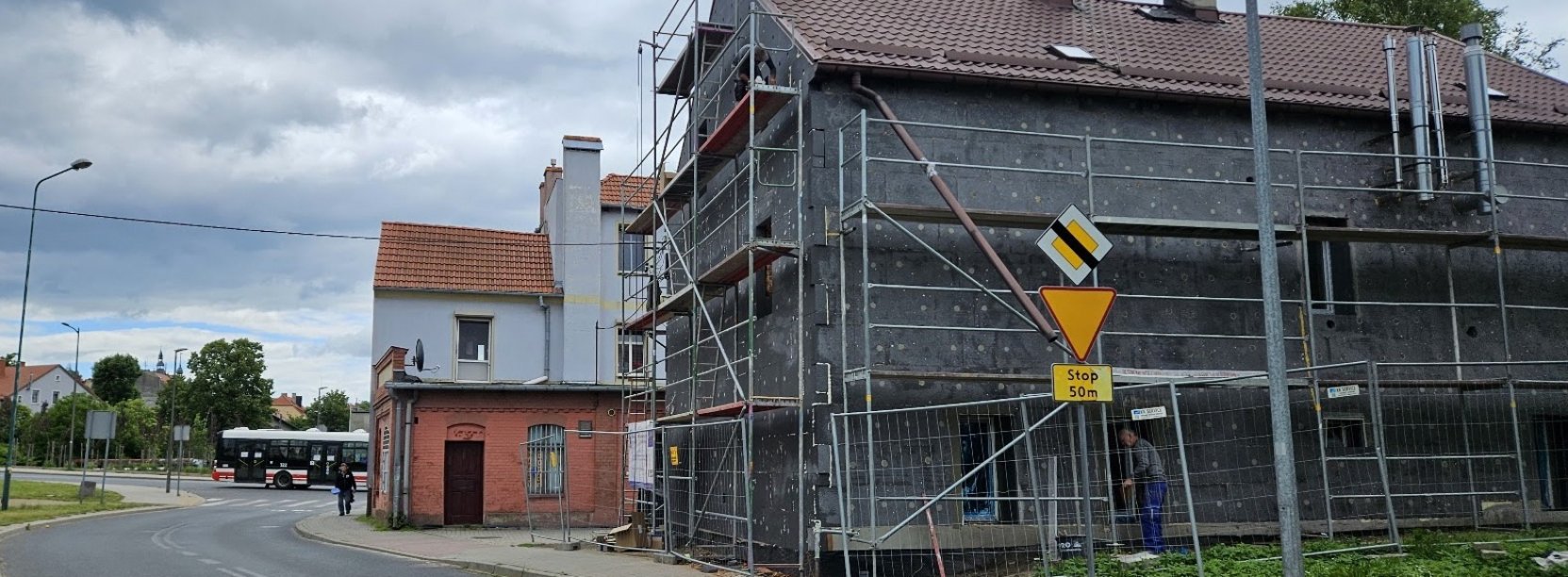Dom wielorodzinny, rusztowania, elewacja w budynku obłożona szarym styropianem