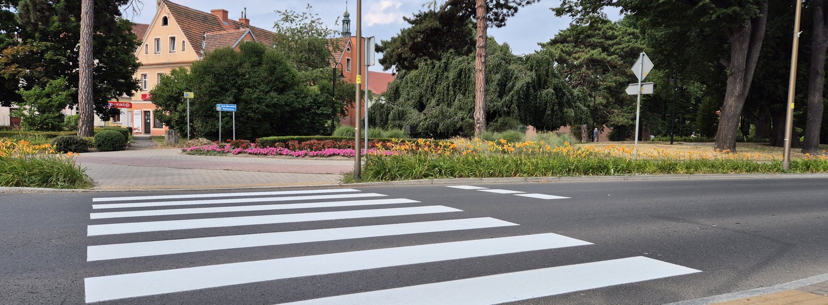 Przejście dla pieszych zaraz po namalowaniu, za przejściem mała kamienica i park