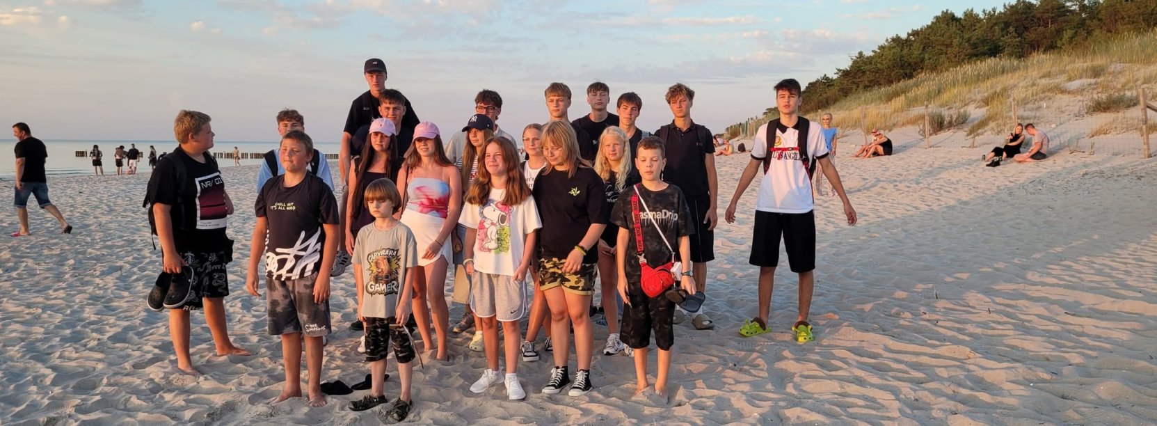 Grupa młodzieży na plaży, po prawej wydmy