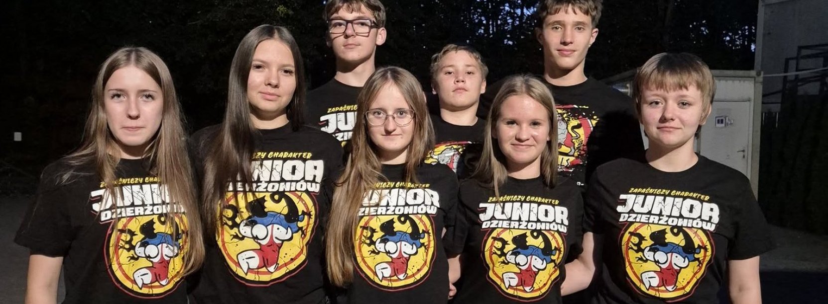 Grupowe zdjęcie zawodniczek i zawodników w jednakowych czarnych koszulkach z logotypem klubu