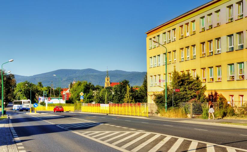 Ulica wrocławska w Dzierzoniowie. Widok na drogę i budynek szkoły, w tle Góry Sowie