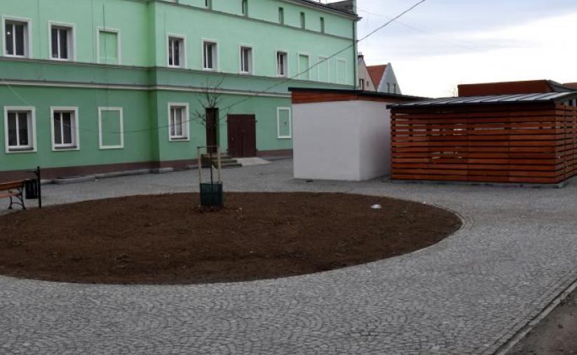 Widok na zieloną kamienicę i miejsce do segregacji odpadów