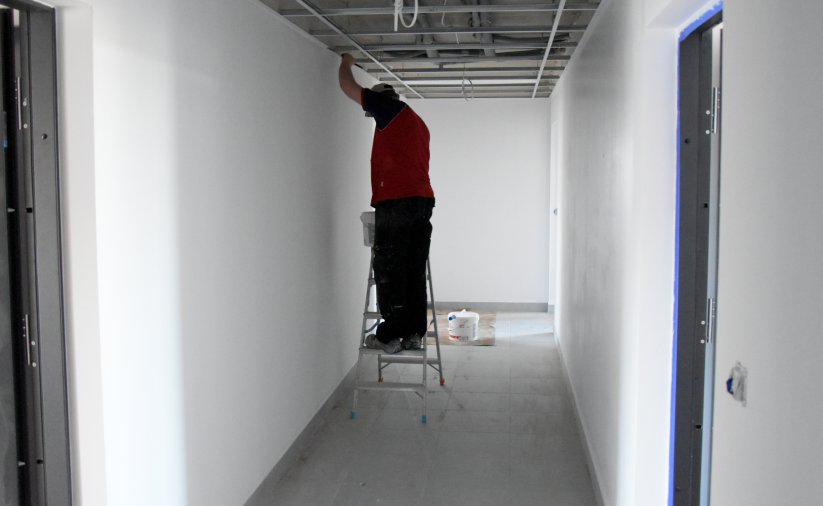 Pracownik montujący instalaję elektryczną na korytarzu