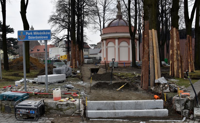 Wejśćie do parku, po lewej tabliczka z nazwą, na dole materiały i narzędzia budowlane