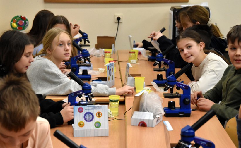 Grupa uczniów pracujących z mikroskopami