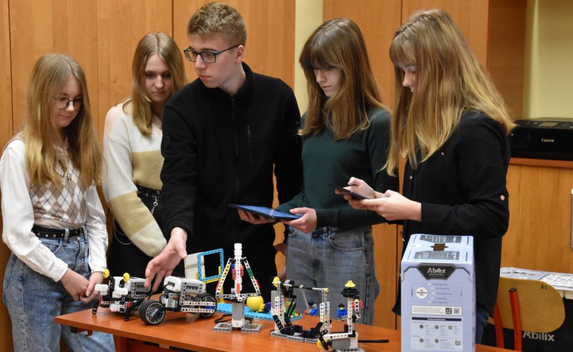 Grupa młodych uczniów ze zrobionymi przez siebie robotami