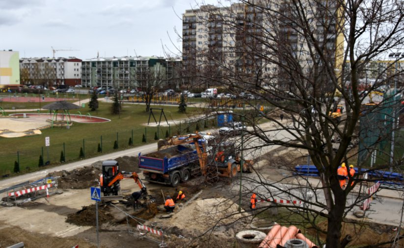 Skrzyżowanie dróg osiedlowych widziane z góry, w tle wieżowce