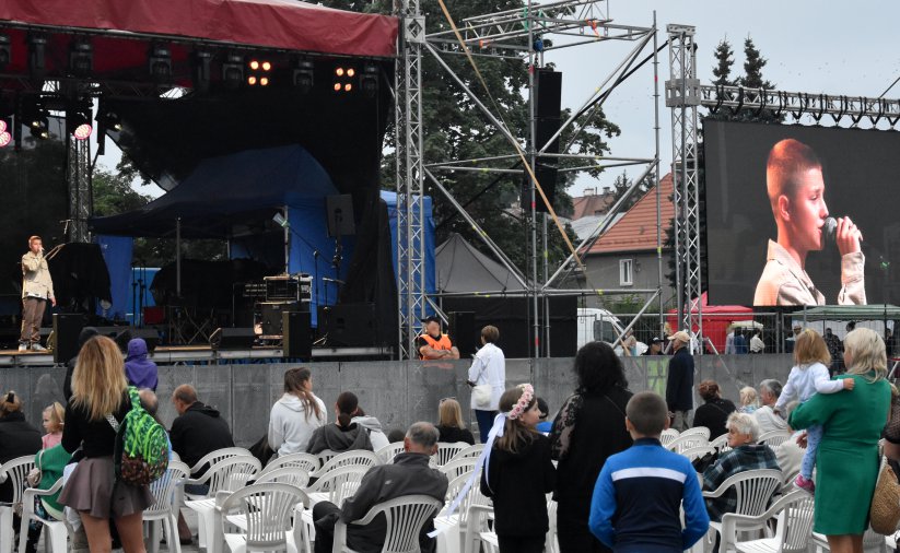 Scena koncertowa, obok sceny duży monitor pokazujący śpiewającego chłopca