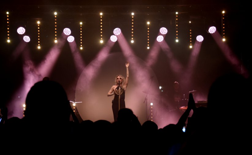 Koncert nocą, na scenie artystka, dookoła niej fioletowe światła