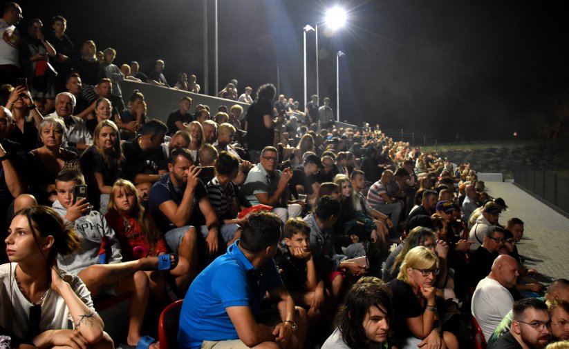 Stadion wieczorem z trybuną wypełnioną kibicami 