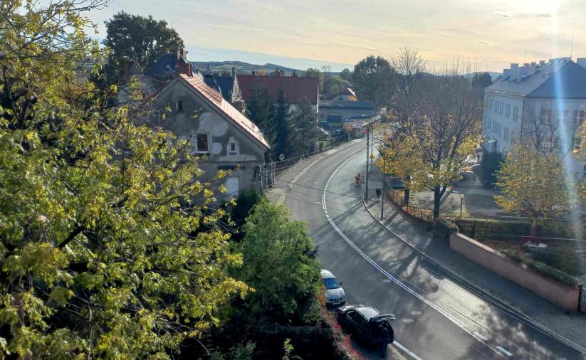 Droga łukiem skręcająca w prawo widziana z góry, po lewej korona drzewa