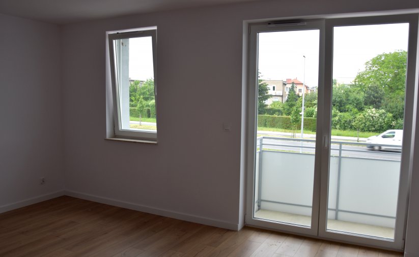 Pokój z białymi ścianami oknem i drzwiami balkonowymi