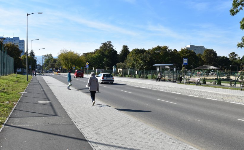 Ścieżka rowerowa, chodnik i wyremontowana droga, za nią park miejski