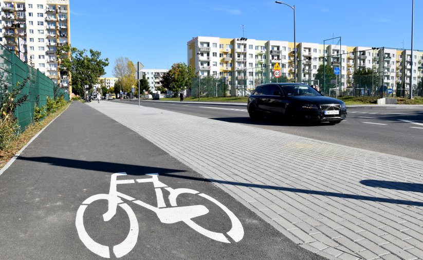 Ścieżka rowerowa i chodnik, po drodze drodze osiedlowej jedzie samochów