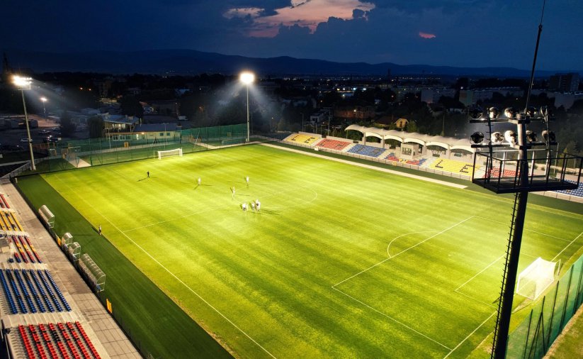 Stadion nocą z zieloną murawą i włączanymi światłami na masztach