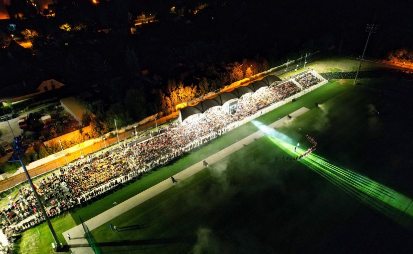 Podświetlona trybuna stadionu z kibicami i boisko piłkarskie