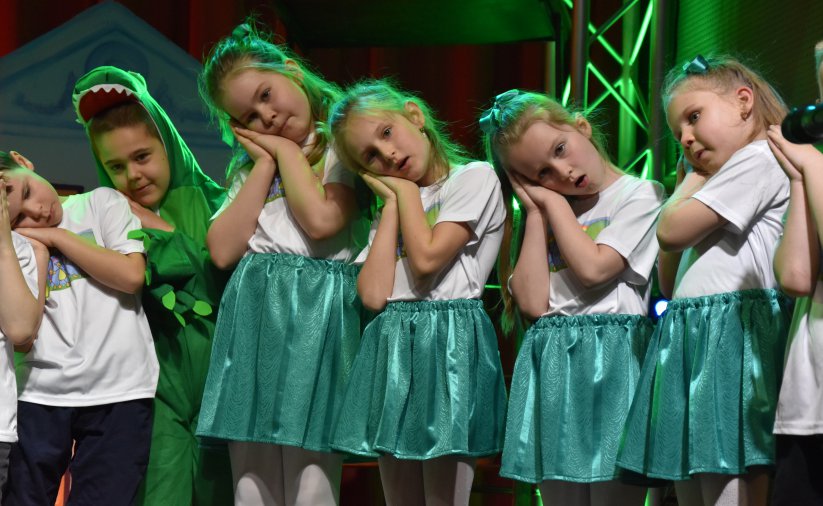 Dzieci w biało-zielonych strojach na scenie