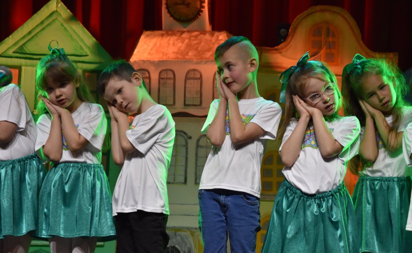 Dzieci w biało-zielonych strojach na scenie