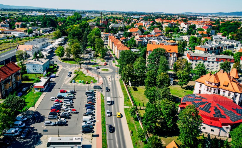 Droga, parkingi i budynki z góry otoczone dużymi drzewami