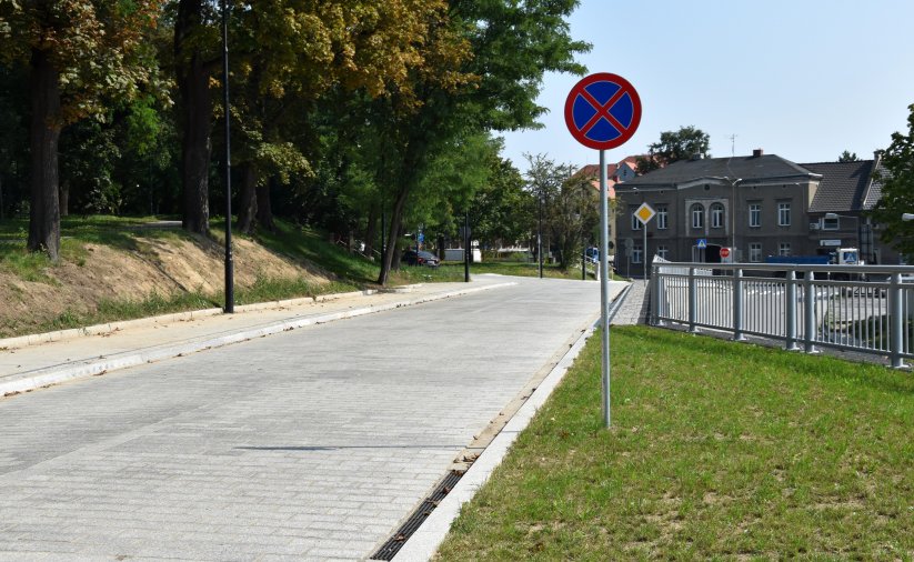 Droga z kamiennej kostki, po bokach zieleń i drzewa