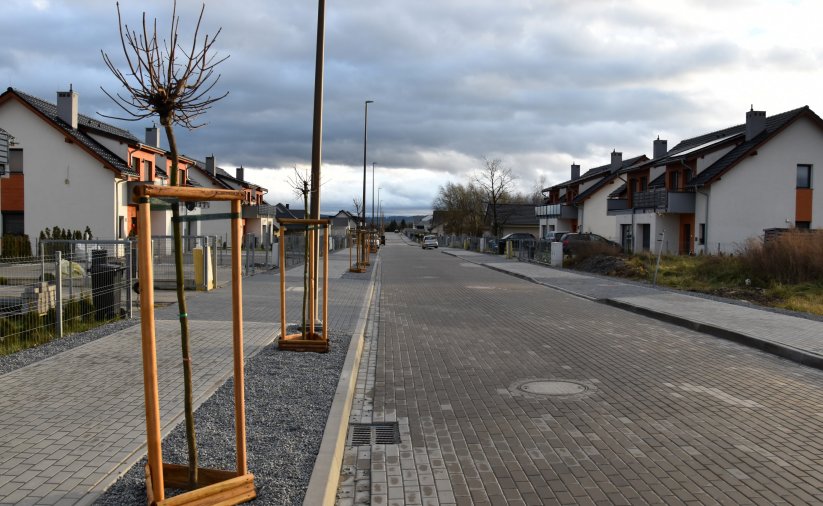 Ulica osiedlowa z kostki betonowej, po bokach domy