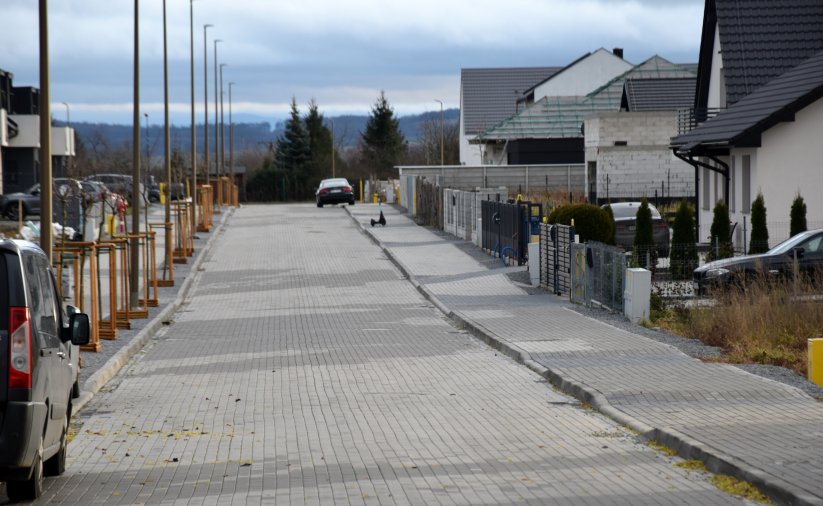 Osiedlowa ulica z kostki betonowej, wdłuż ulicy domy jednorodzinne