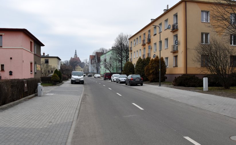 Asfatowa droga po remoncie, po bokach domy jedno i wielorodzinne