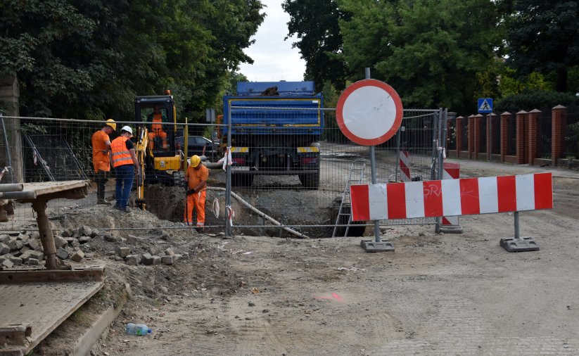 Pracownicy w pomarańczowych kamizelkach przy wykopie w remontowanej drodze