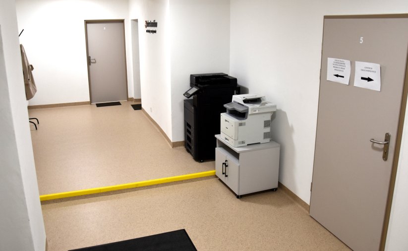 Korytarz, przy ścianie dwie duże drukarki