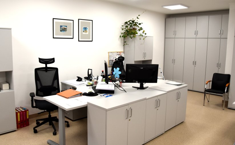 Biuro, dwa stanowiska pracy, w tle szafki