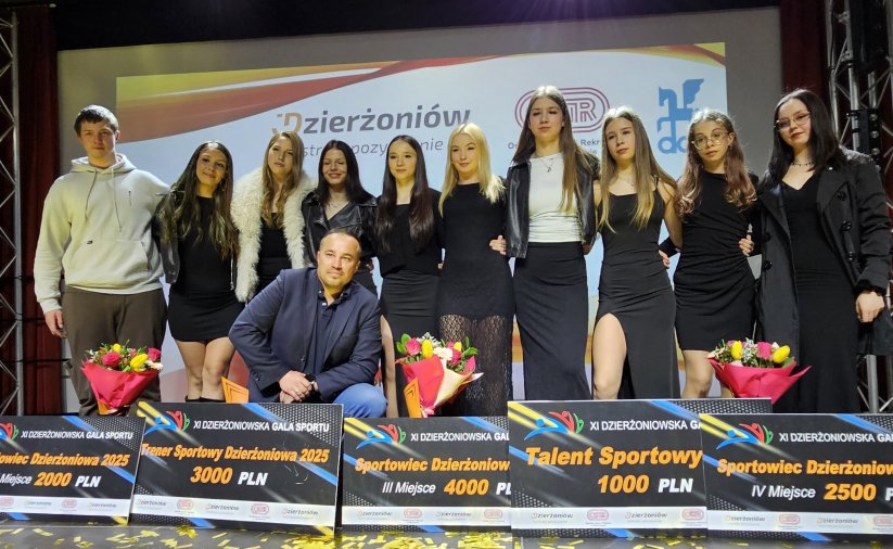 Grupowe zdjecie zapaśniczek na scenie, po środku trener