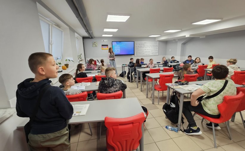 Duża klasa, uczniowie siedzą w ławkach zamiast tablicy ekran multimedialny